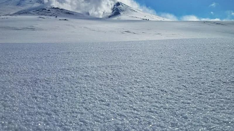 Feather snow with a steaming Asahidake behind